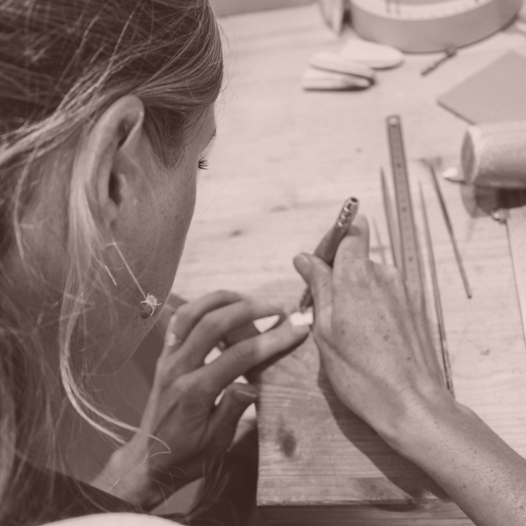 Hands at the goldsmith bench marking a silver heart from the #allheartsunderoneroof collection.